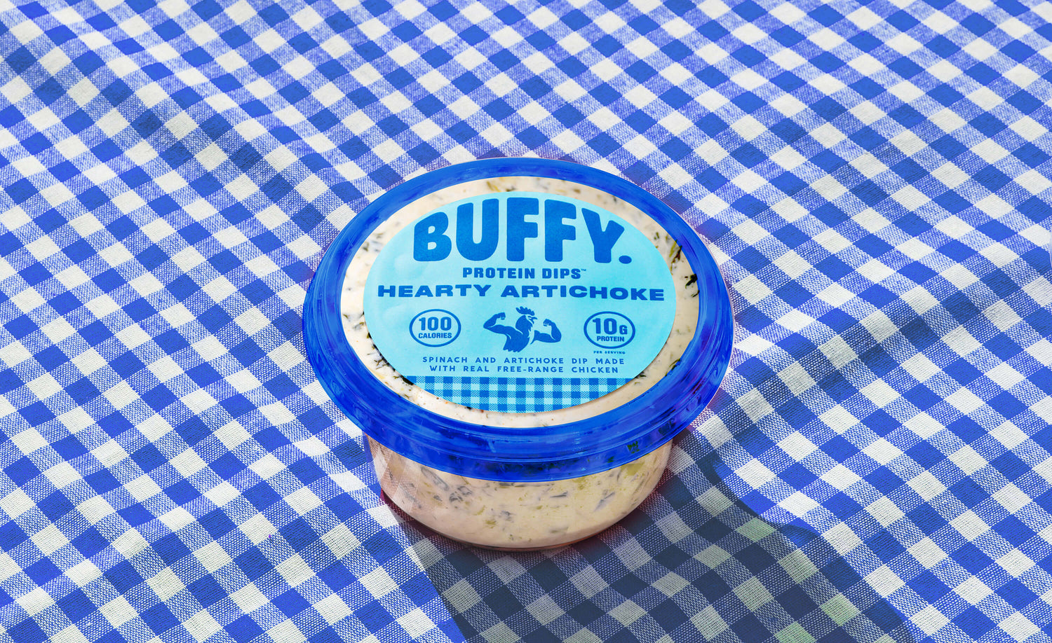 Buffy Protein Dips Hearty Artichoke sitting on a blue and white checkered picnic blanket