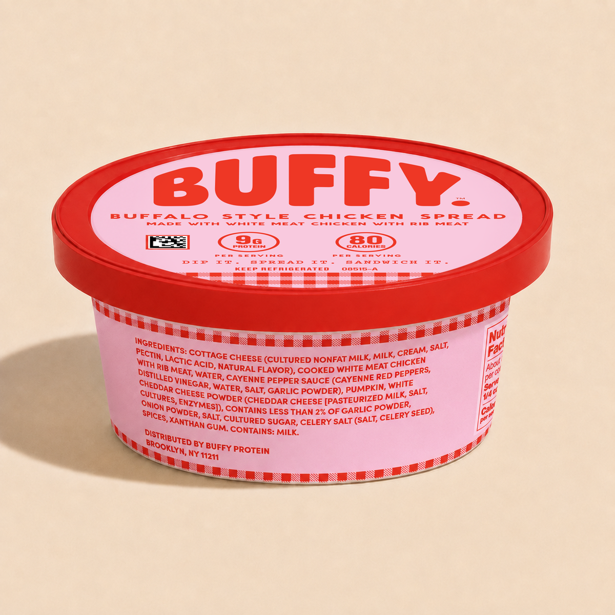 A tub of BUFFY Buffalo Style Chicken Spread on a warm beige background. The product is in a clear plastic tub showing the ingredients list with a red lid featuring the brand name 'BUFFY' in bold red letters.