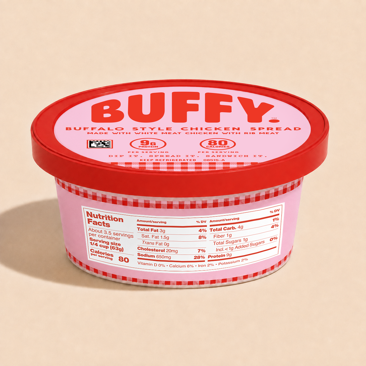 A tub of BUFFY Buffalo Style Chicken Spread on a warm beige background. The container has a pink body with a red gingham pattern, a red lid with bold red lettering, and a white nutrition facts label on the front.